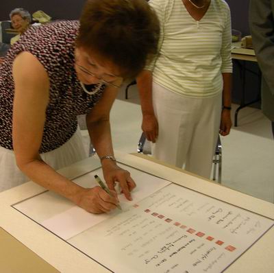 Leona Kelly signs Sumi-e Artists of Canada scroll with her seal 