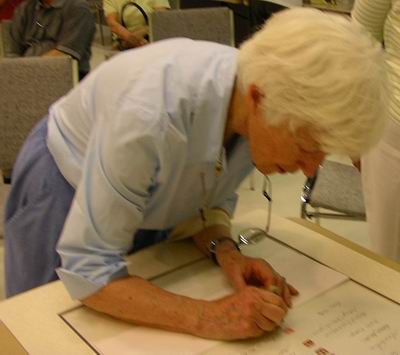 Ann Abraham signs Sumi-e Artists of Canada scroll with her seal 