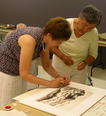 Leona Kelly puts seal on painting helped by Marie Ikeda