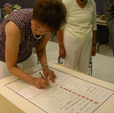 Leona Kelly signs Sumi-e Artists of Canada scroll with her seal